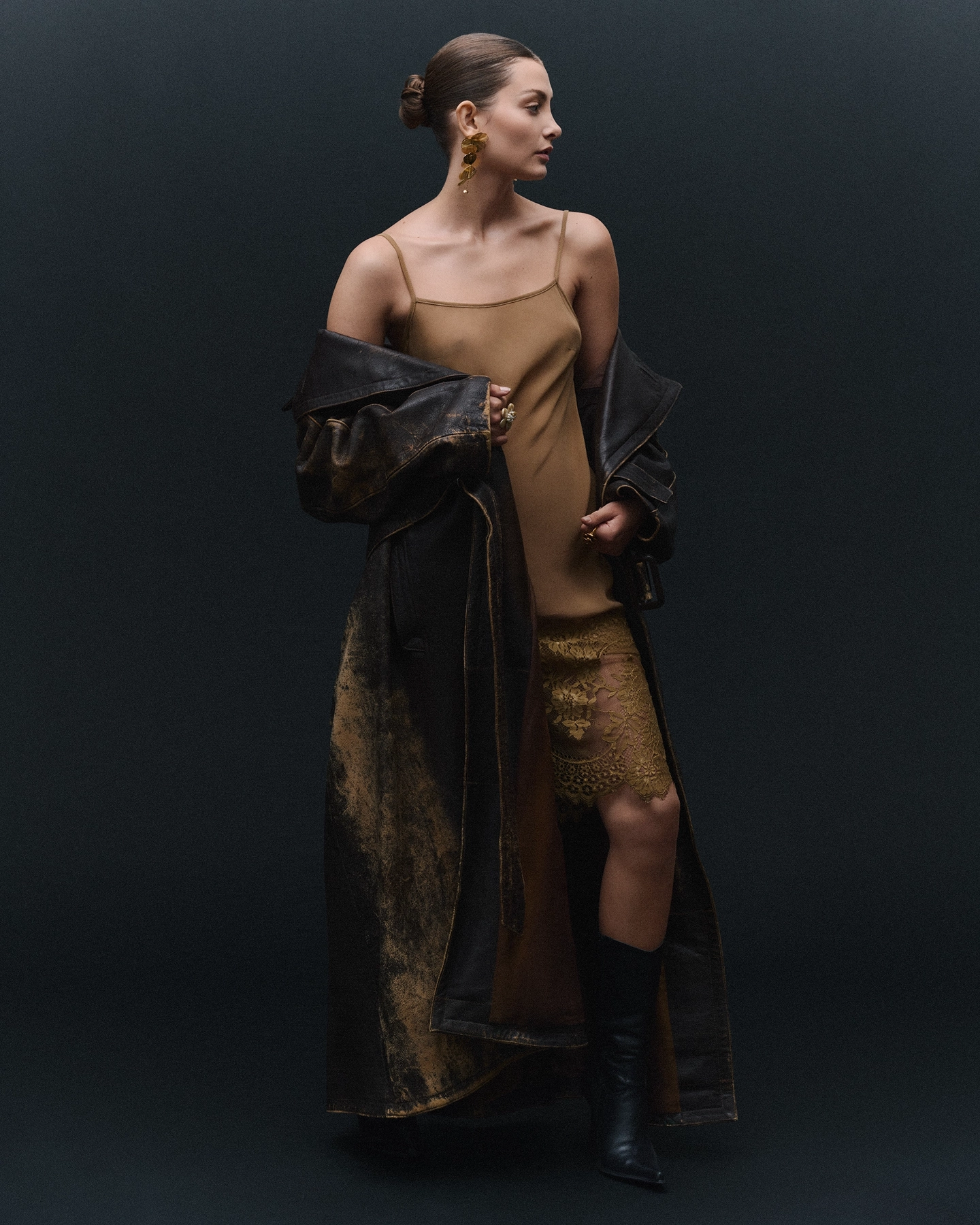 Alice L in gold slip dress with draped leather coat on dark backdrop for Sicky Magazine, styled by Olof Runmarker, makeup by Denise Löfstrand