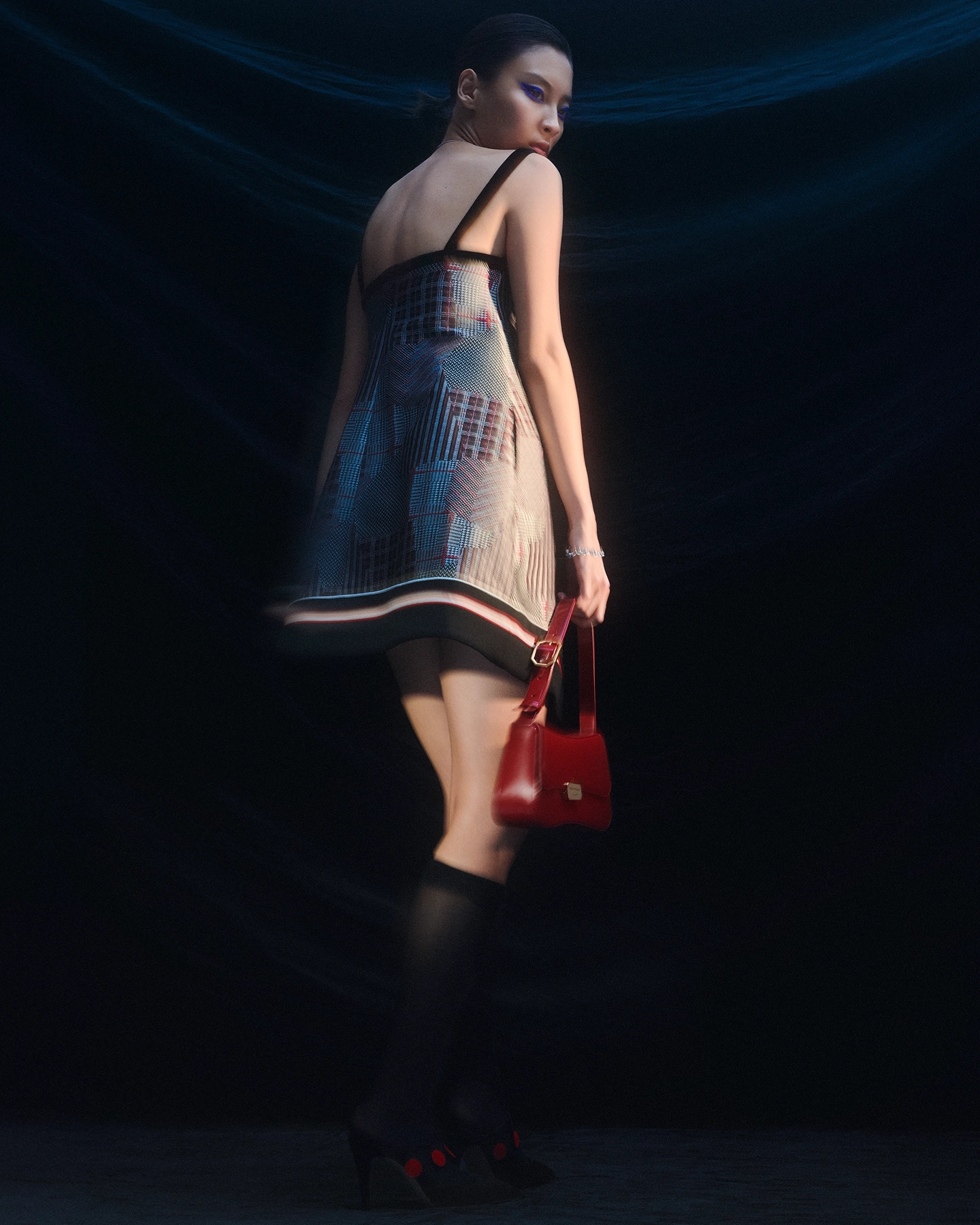 Model in printed slip dress with red handbag in atmospheric dark studio lighting for 5 Eleven Magazine, styled by Joanne Kennedy, makeup by Adam De Cruz