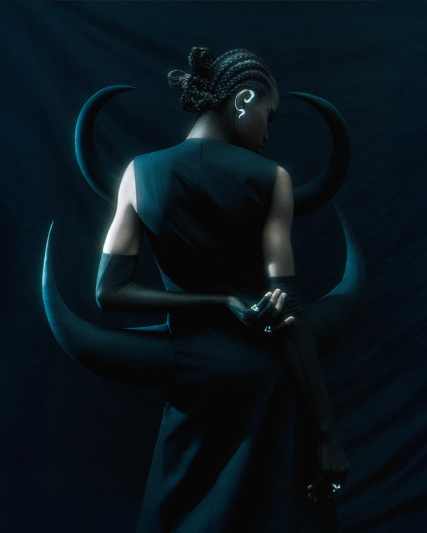 Gifty seen from behind in dark structured top with braided updo against teal backdrop for Schon Magazine, styled by Carlos Mangubat, hair by Bjorn Krischker