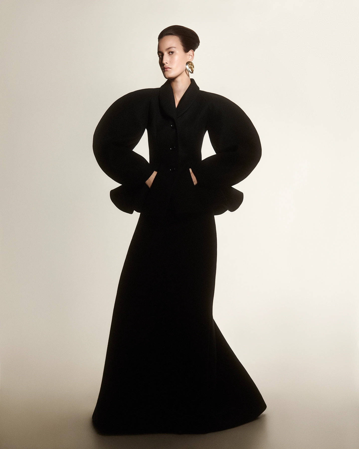 Model in sculptural black floor-length coat with exaggerated puff sleeves for Harpers Bazaar Arabia