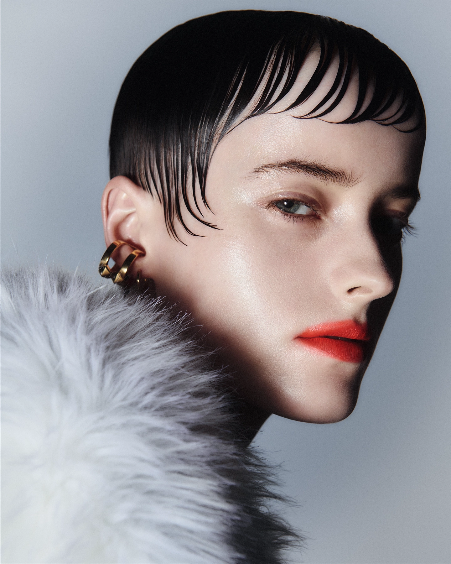 Profile with slicked short hair, red lip, fur collar and gold hoop earring for Vogue Philippines and Vogue Turkiye, makeup by Adam De Cruz, hair by Bjorn Krischker, styled by Carlos Mangubat
