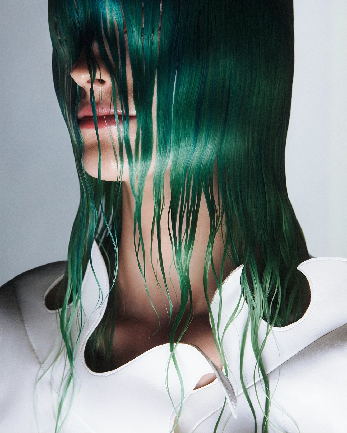 Portrait with emerald green wet hair cascading over face against white backdrop for Vogue Philippines and Vogue Turkiye, makeup by Adam De Cruz, hair by Bjorn Krischker, styled by Carlos Mangubat