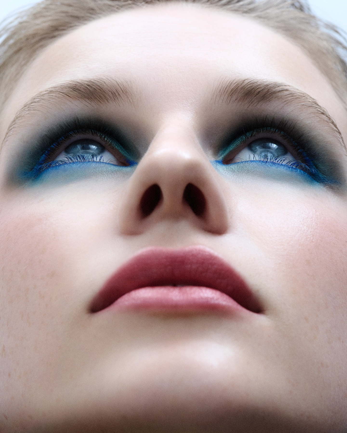 Ellen close-up looking upward with smoky black and electric blue eyeliner, low angle beauty portrait