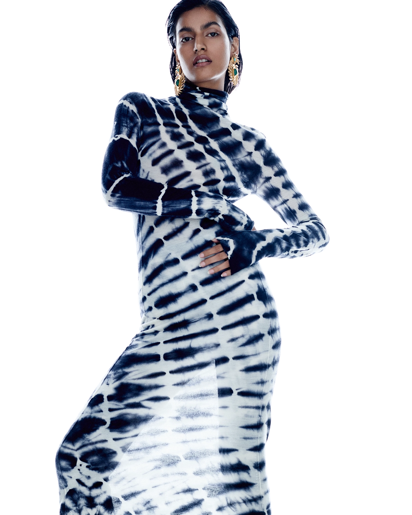 Chavvi Dhiman in black and white tie-dye turtleneck dress with gold earrings on white background for Vogue Arabia, styled by Joanne Kennedy