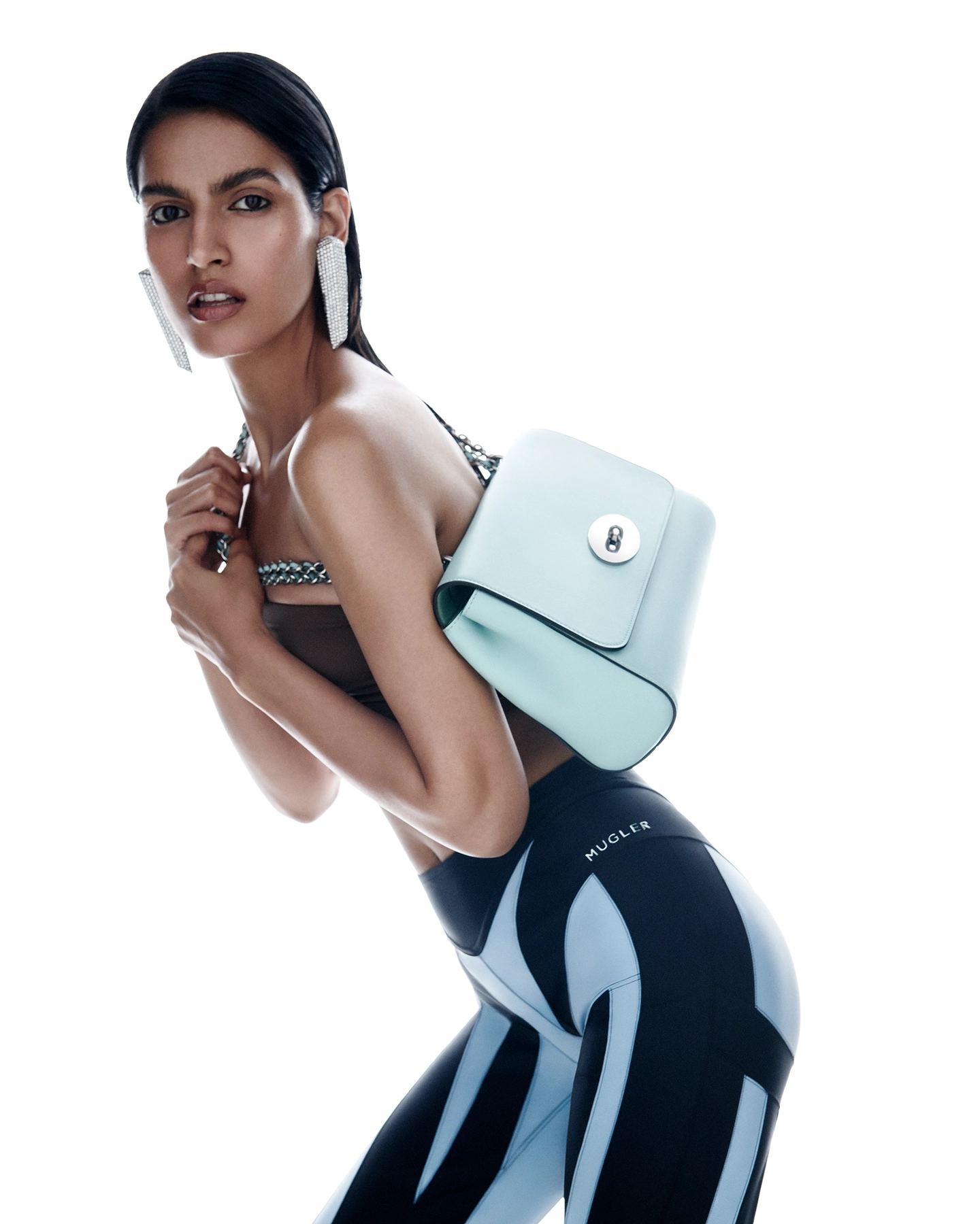 Chavvi Dhiman in athletic leggings and halter top carrying mint green bag, looking over shoulder for Vogue Arabia, styled by Joanne Kennedy
